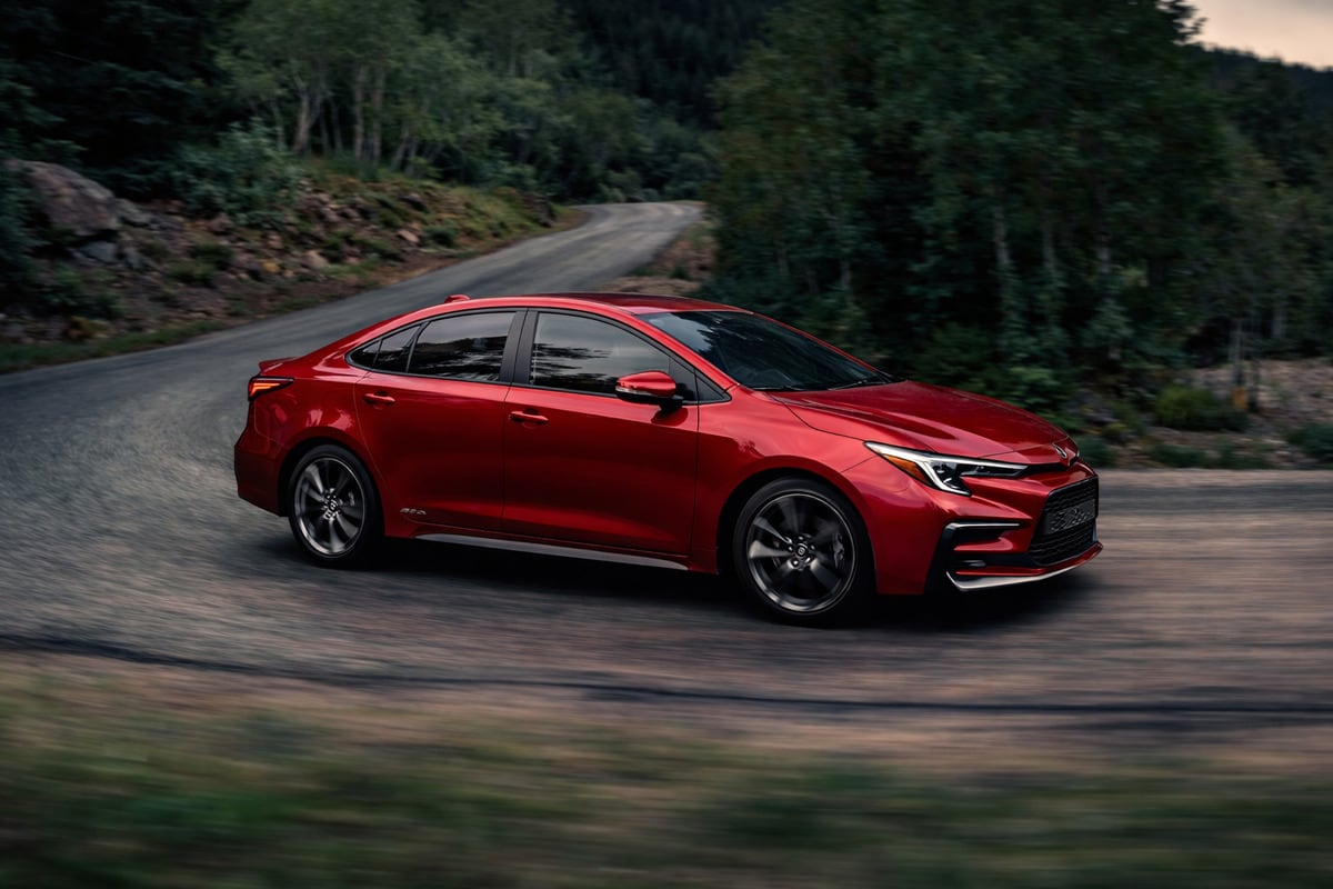 Червен седан Toyota Corolla в движение по горски път
