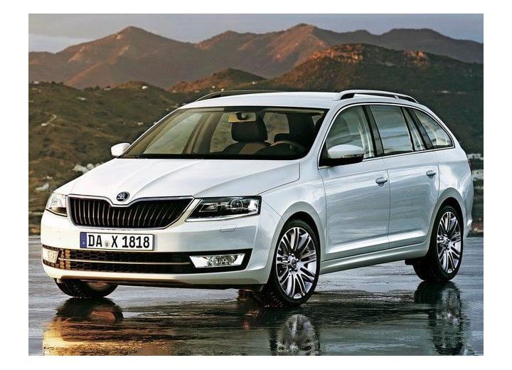 Бяло комби Škoda Octavia III на морски бряг с планини на заден план